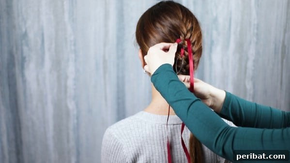 Sweet Ribbon Braid Style 11 The ribbon is being expertly woven into the braid, demonstrating how to alternate sides to create an intricate pattern down the hair.