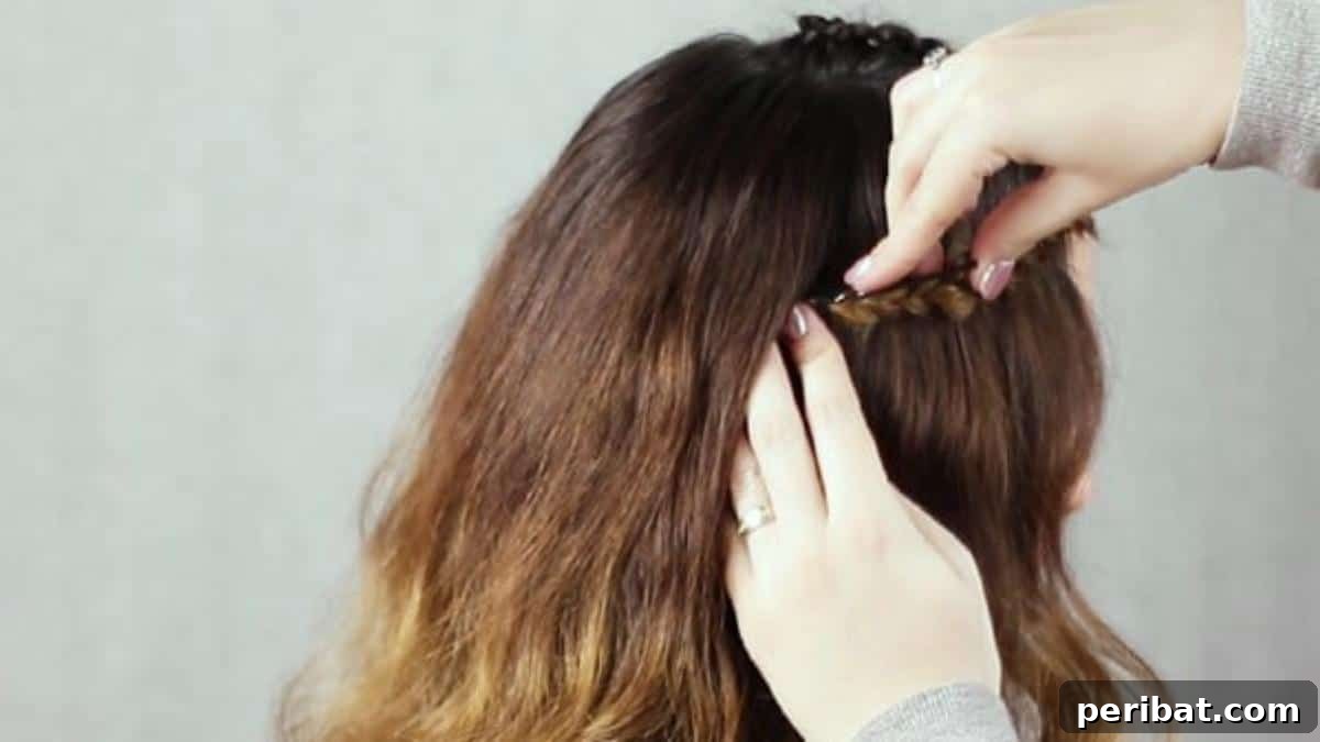 Regal Braided Crown Updo Video Steps 13 Step 5: Tucking and pinning the end of the braid underneath the hair.