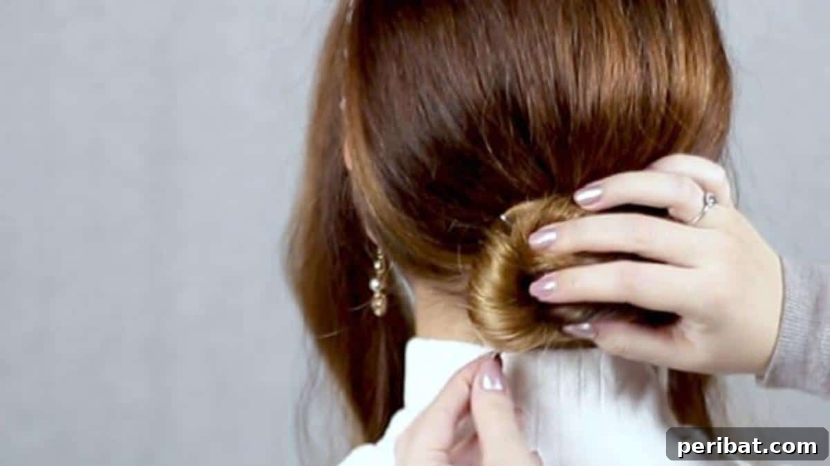 Chic Low Braided Updo Tutorial 11 Securing the intricately coiled bun with multiple bobby pins for strong hold