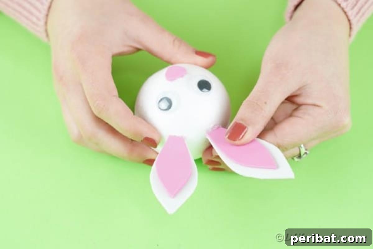DIY Adorable Easter Bunny Wreath Video Guide 13 Gluing the paper ears to the top of the styrofoam bunny head.