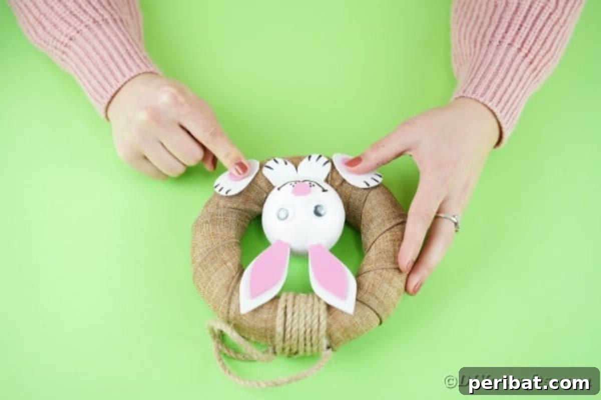 DIY Adorable Easter Bunny Wreath Video Guide 16 Attaching the paper feet and front paws to the burlap bunny wreath.