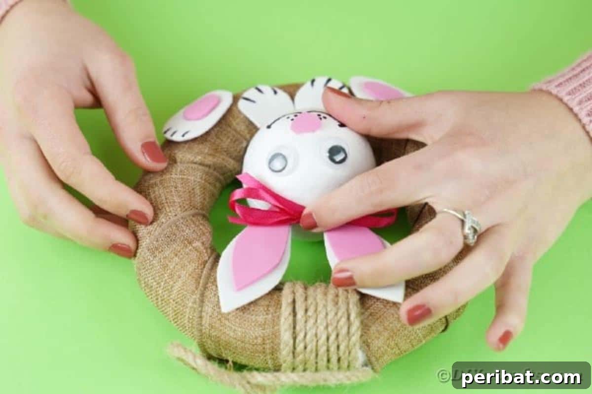 DIY Adorable Easter Bunny Wreath Video Guide 17 Gluing a small pink satin bow between the bunny's ears.