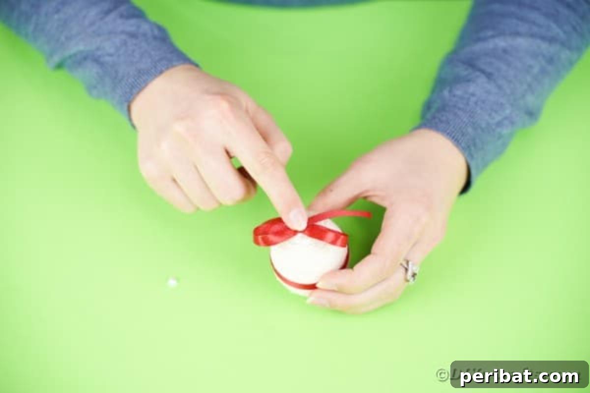 Crafting Yarn Wrapped Easter Eggs 10 Attaching a red bow to the top of the yarn wrapped Easter egg
