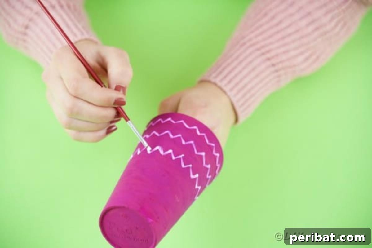 Turn Plastic Cups Into Charming Owls 8 Using a paintbrush tip to add decorative lines to the painted cup.