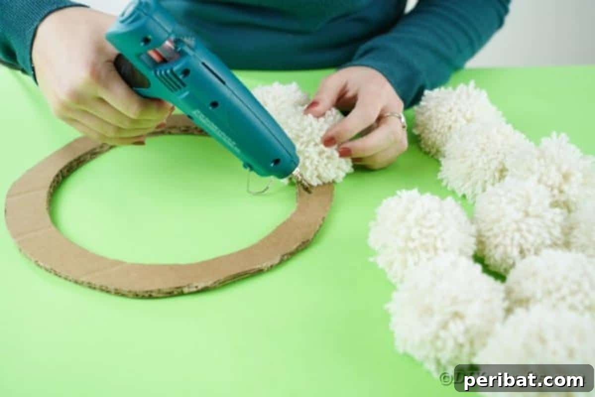 Fluffy Pom Pom Easter Bunny Door Wreath 12 Gluing fluffy pom poms onto the cardboard wreath frame.