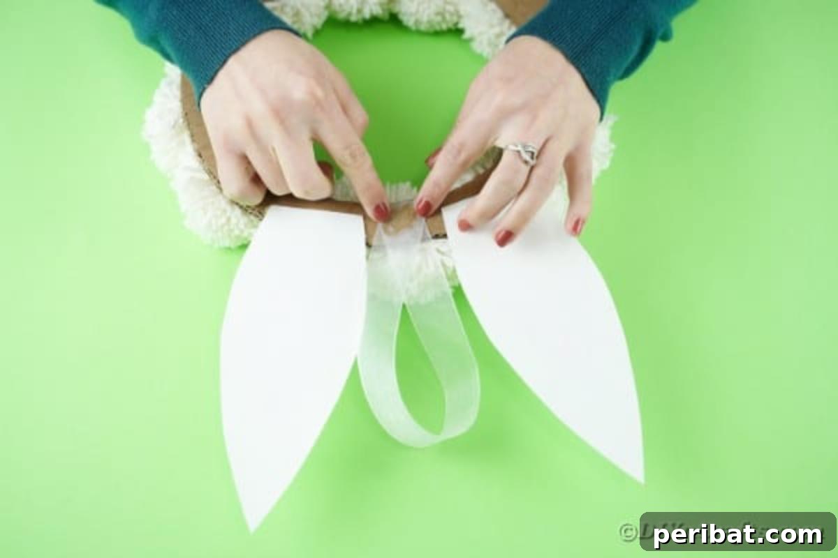 Fluffy Pom Pom Easter Bunny Door Wreath 17 Adding a ribbon loop to the back of the pom pom wreath for easy hanging.