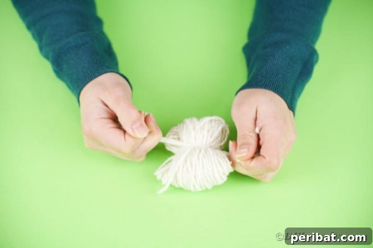 Fluffy Pom Pom Easter Bunny Door Wreath 8 Tying a separate piece of yarn around the middle of the wrapped yarn bundle.