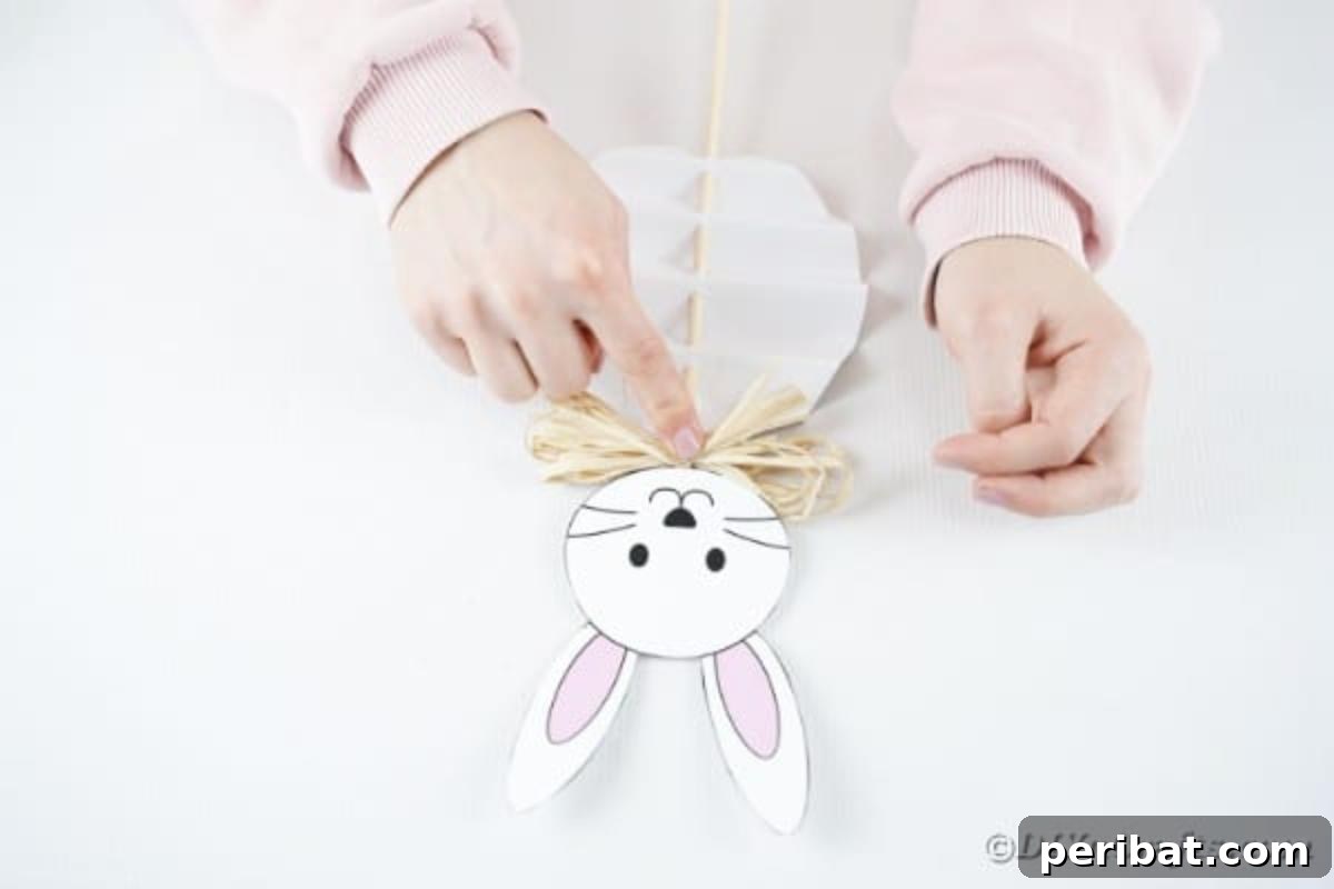 DIY Easter Paper Bunny Craft Free Printable Template 15 Image illustrating the gluing of the twine bow below the bunny's head