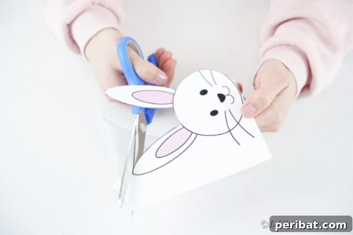 DIY Easter Paper Bunny Craft Free Printable Template 9 Image showing hands carefully cutting out the bunny head shape