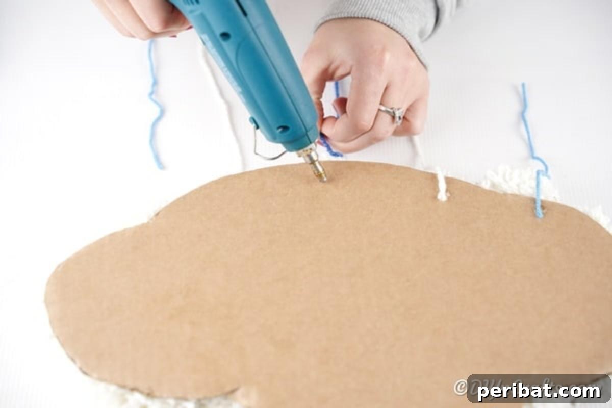 Attaching the completed raindrop pom pom strings to the back of the cloud