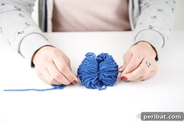 Tying a yarn pom pom in the middle