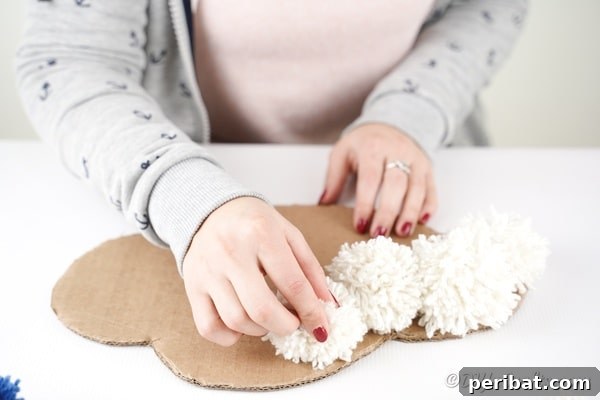 Gluing white pom poms onto the cardboard cloud