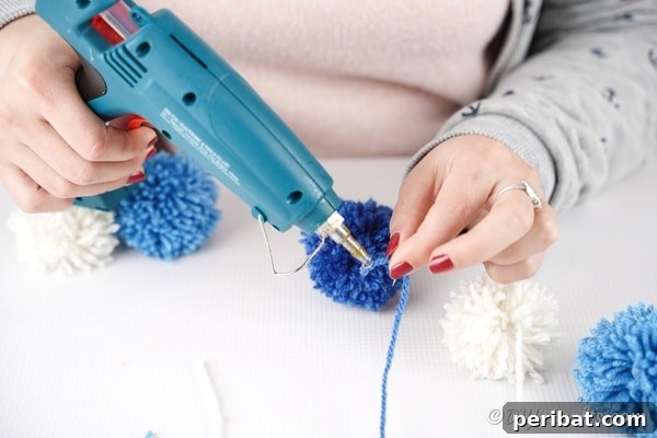 Gluing individual yarn strings to the colorful raindrop pom poms