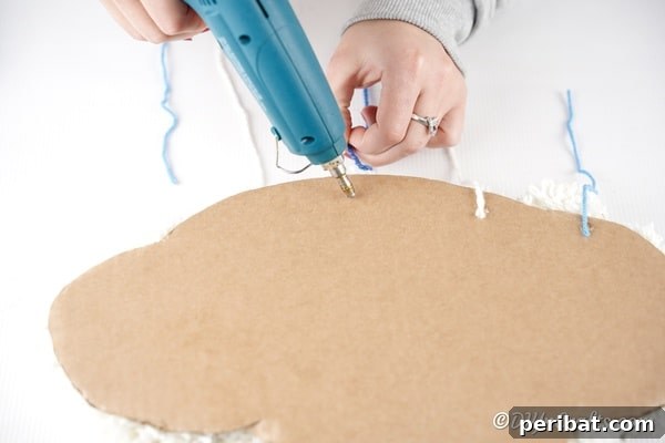 Attaching the raindrop pom pom strings to the back of the cloud
