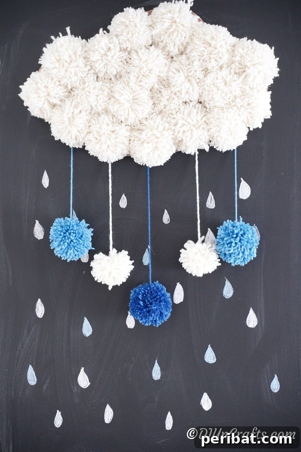 Completed yarn pom pom cloud art displayed on a chalkboard