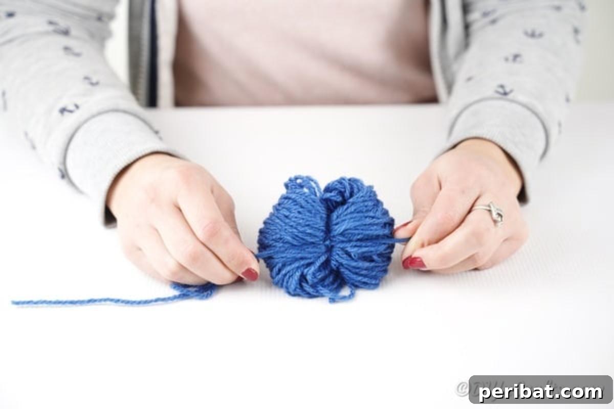 Tying a yarn pom pom in the middle after wrapping