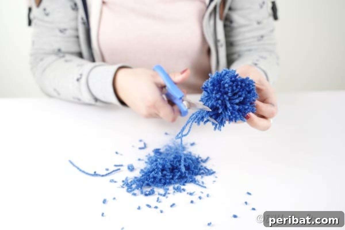 Trimming the edges of a yarn pom pom into a perfect sphere