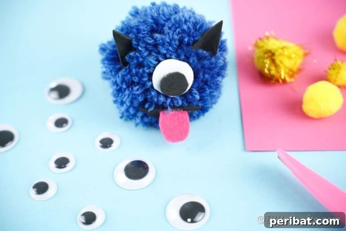 Finished blue yarn pom pom monster on a blue background, looking cute
