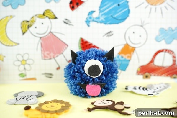 Yarn pom pom monster on colorful craft paper