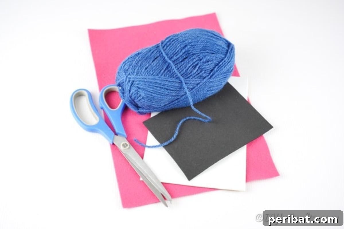 Crafting supplies laid out for making a yarn pom pom monster including yarn, paper, scissors, and glue