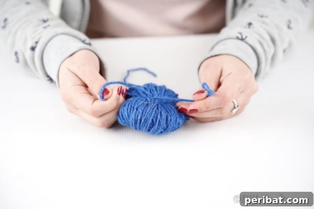 A small piece of yarn being tied around the center of the yarn bundle