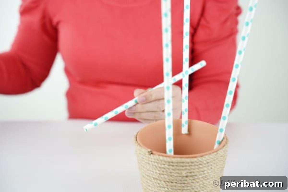 Hoppy Hot Air Balloon Easter Craft 11 Gluing paper straws to the inside rim of a flower pot, creating supports for the hot air balloon