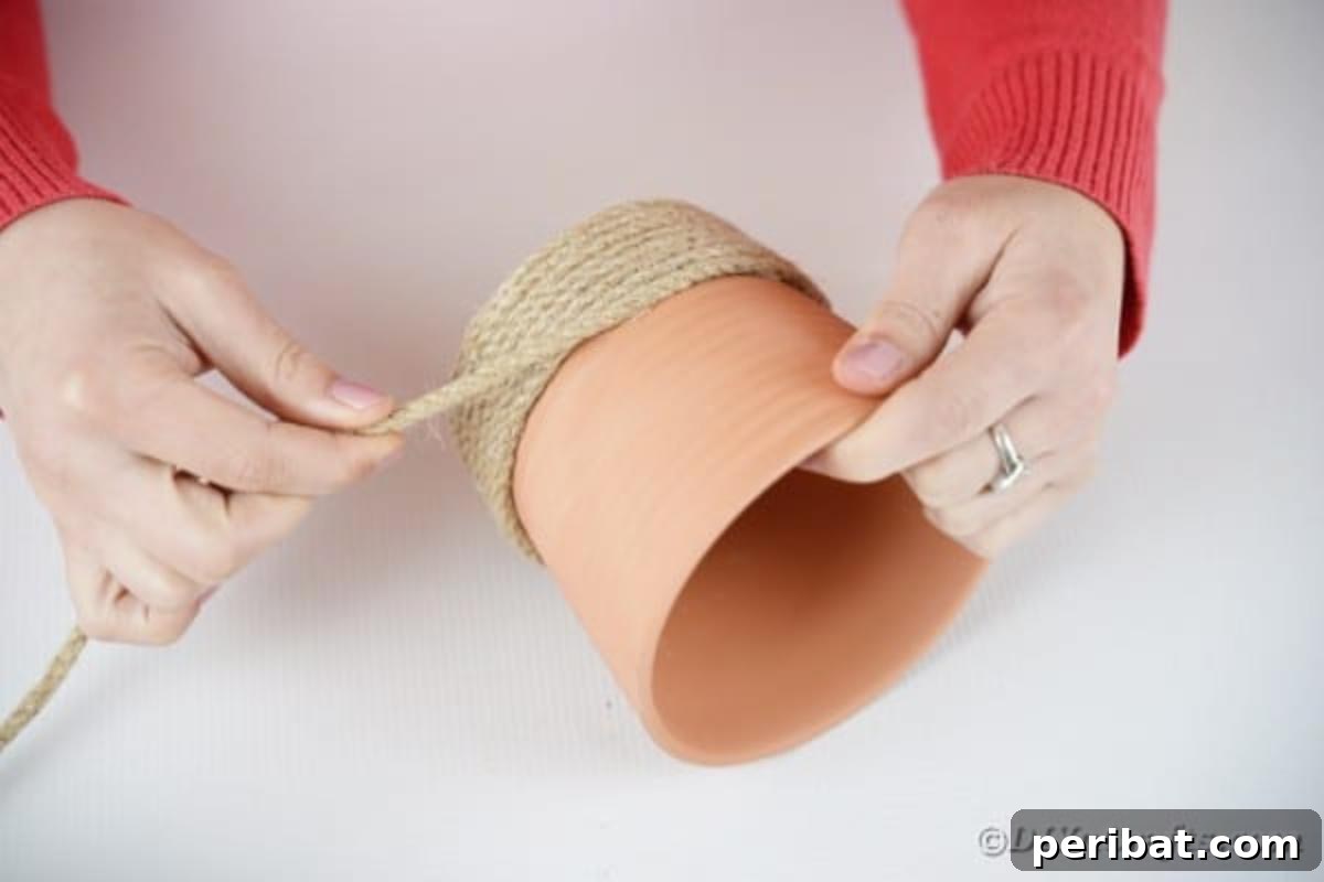 Hoppy Hot Air Balloon Easter Craft 8 Close-up view of gluing twine around a terra cotta pot, starting from the bottom