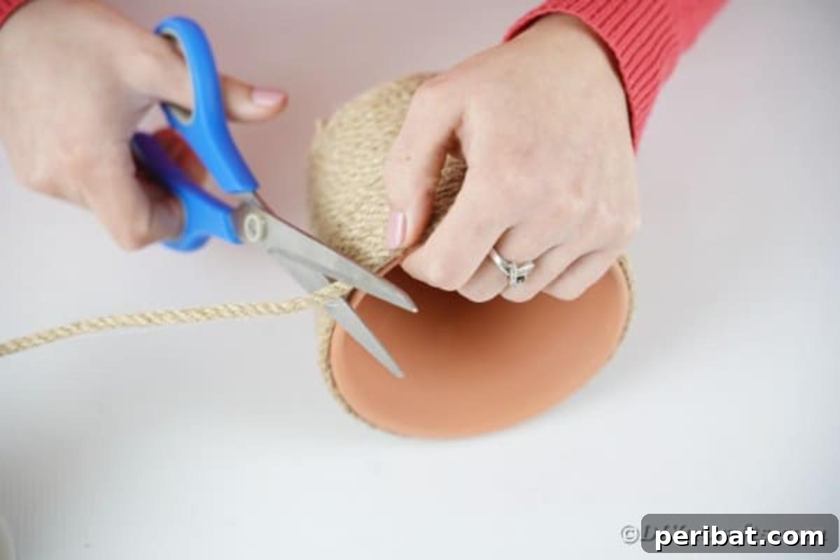 Hoppy Hot Air Balloon Easter Craft 9 Process of cutting off excess twine from a terra cotta pot after wrapping