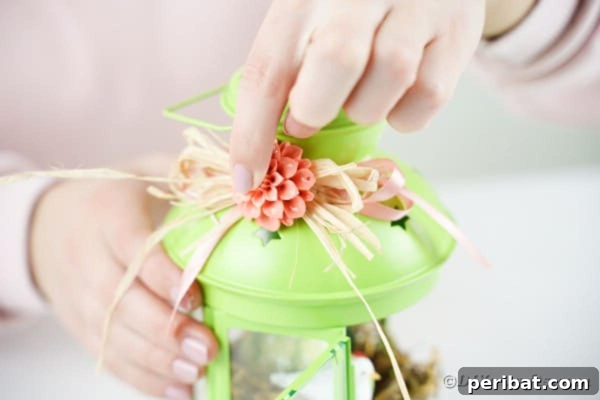 Adding a small artificial flower to the raffia bow on the lantern