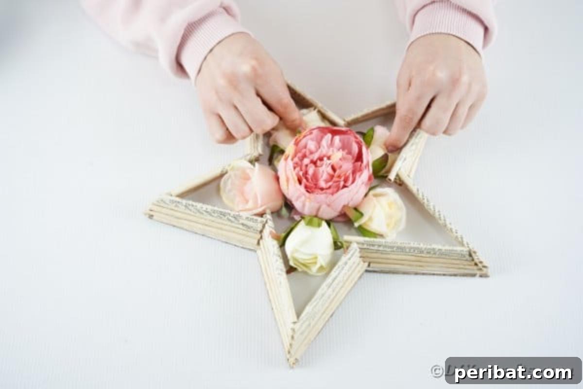 Literary Starburst Wall Decor 16 Artificial flowers being arranged and glued into the center cavity of the book page star, creating a focal point.