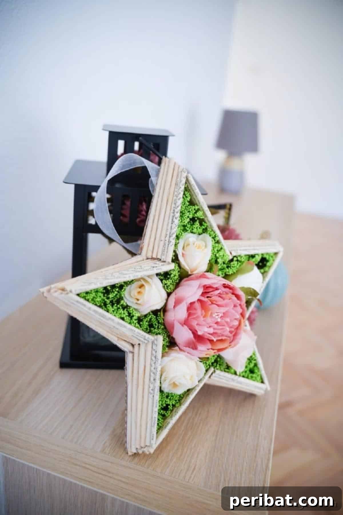 Literary Starburst Wall Decor 3 Handmade paper star art made from book pages, placed next to a vintage lantern on a wooden table, showcasing a warm, rustic aesthetic.