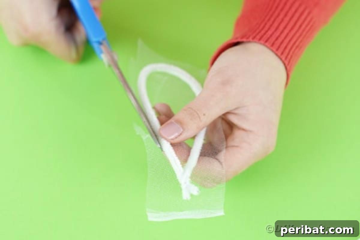 Carefully cutting tulle to fit inside the pipe cleaner ear frame