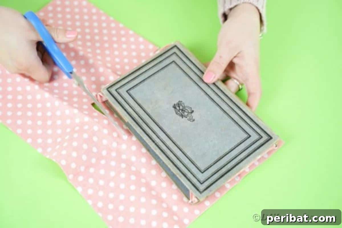 Old Books New Fashion DIY Book Purse Tutorial 11 Measuring a length of chosen fabric against the open book cover to ensure the perfect size for the interior lining of the DIY book purse, focusing on precision