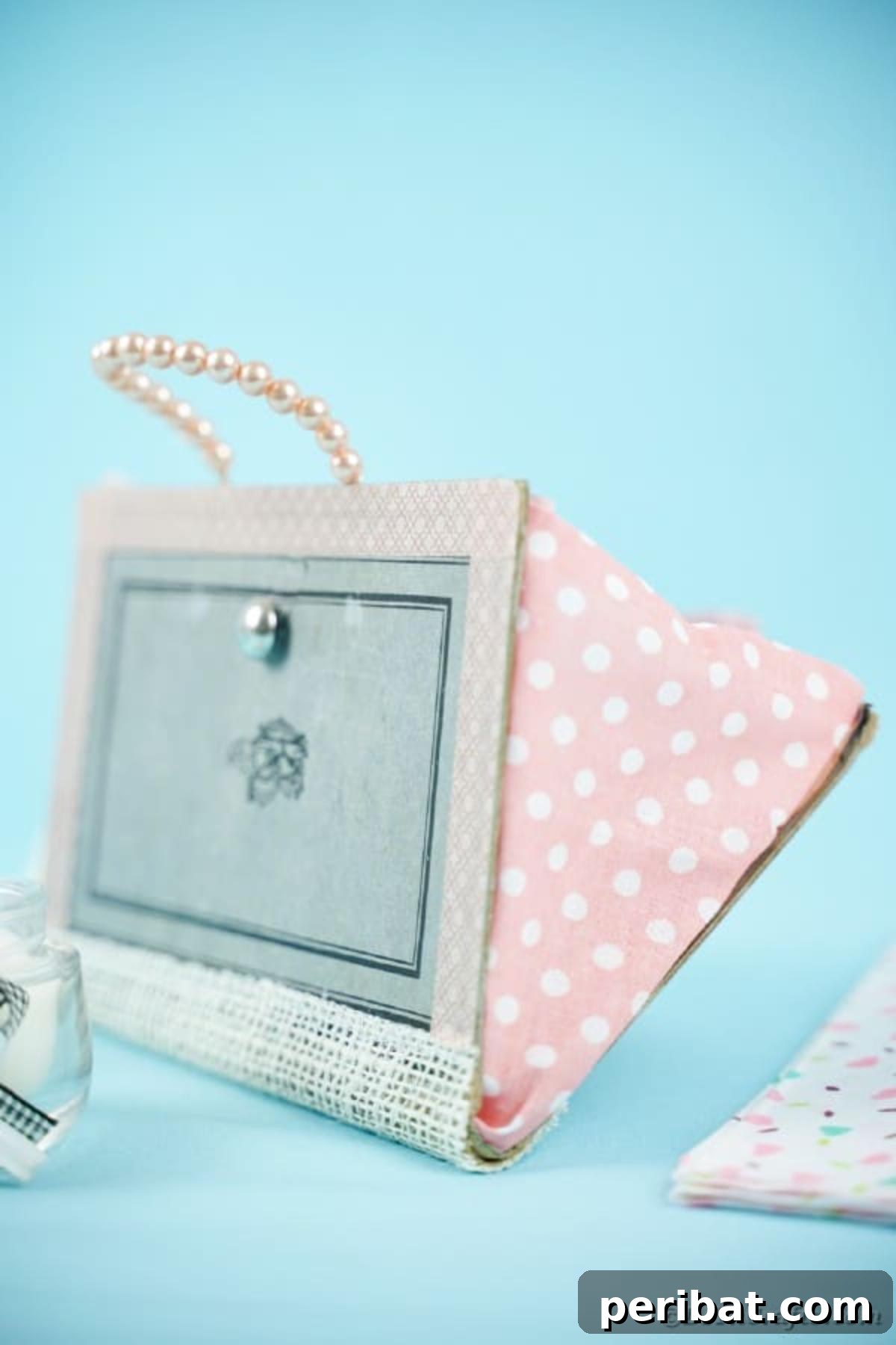 Old Books New Fashion DIY Book Purse Tutorial 18 A beautifully completed upcycled old book purse with a beaded handle, set against a vibrant blue background, ready for its debut as a unique fashion statement