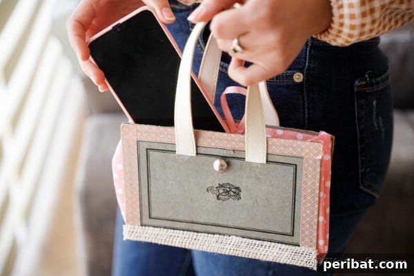 Close-up of a person putting a smartphone into the fashionable upcycled old book purse