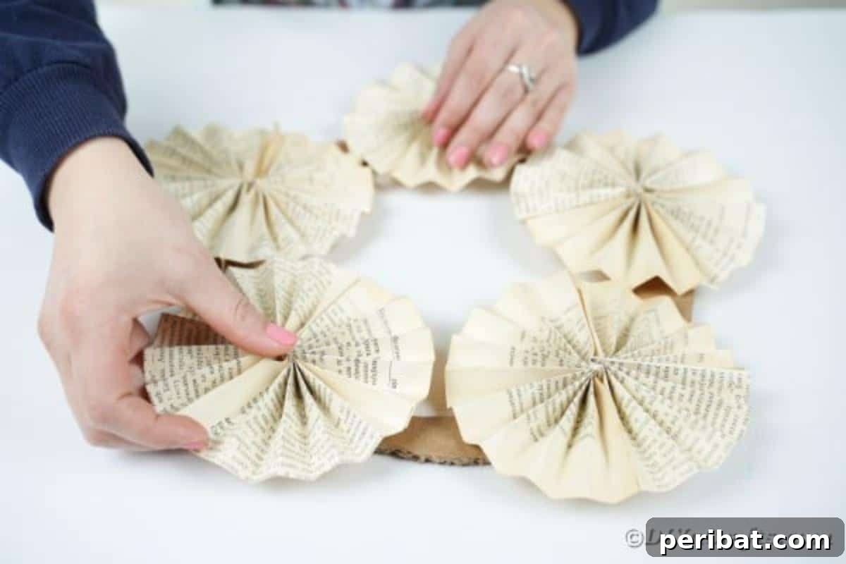 Enchanting Vintage Book Page Wreath Craft 16 Gluing the finished paper fan circles onto the cardboard wreath base, overlapping them to create a full design.