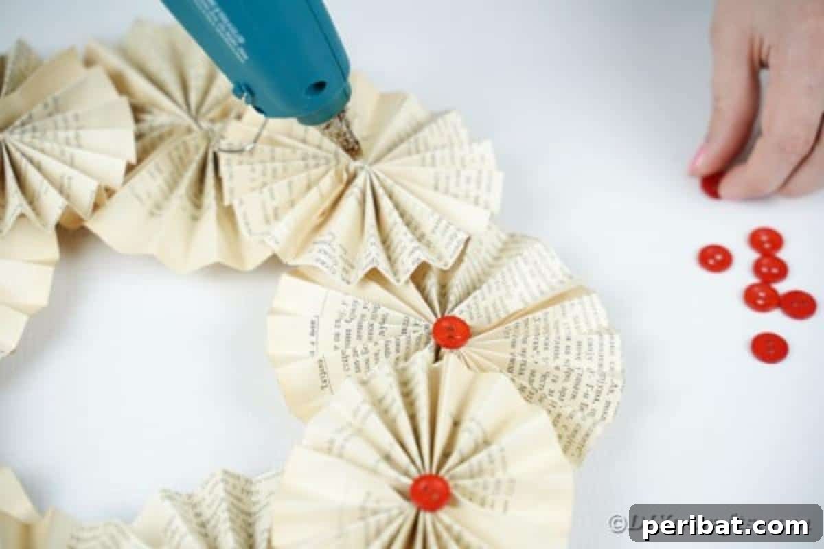 Enchanting Vintage Book Page Wreath Craft 17 Attaching decorative buttons to the center of each paper fan on the wreath for added embellishment.