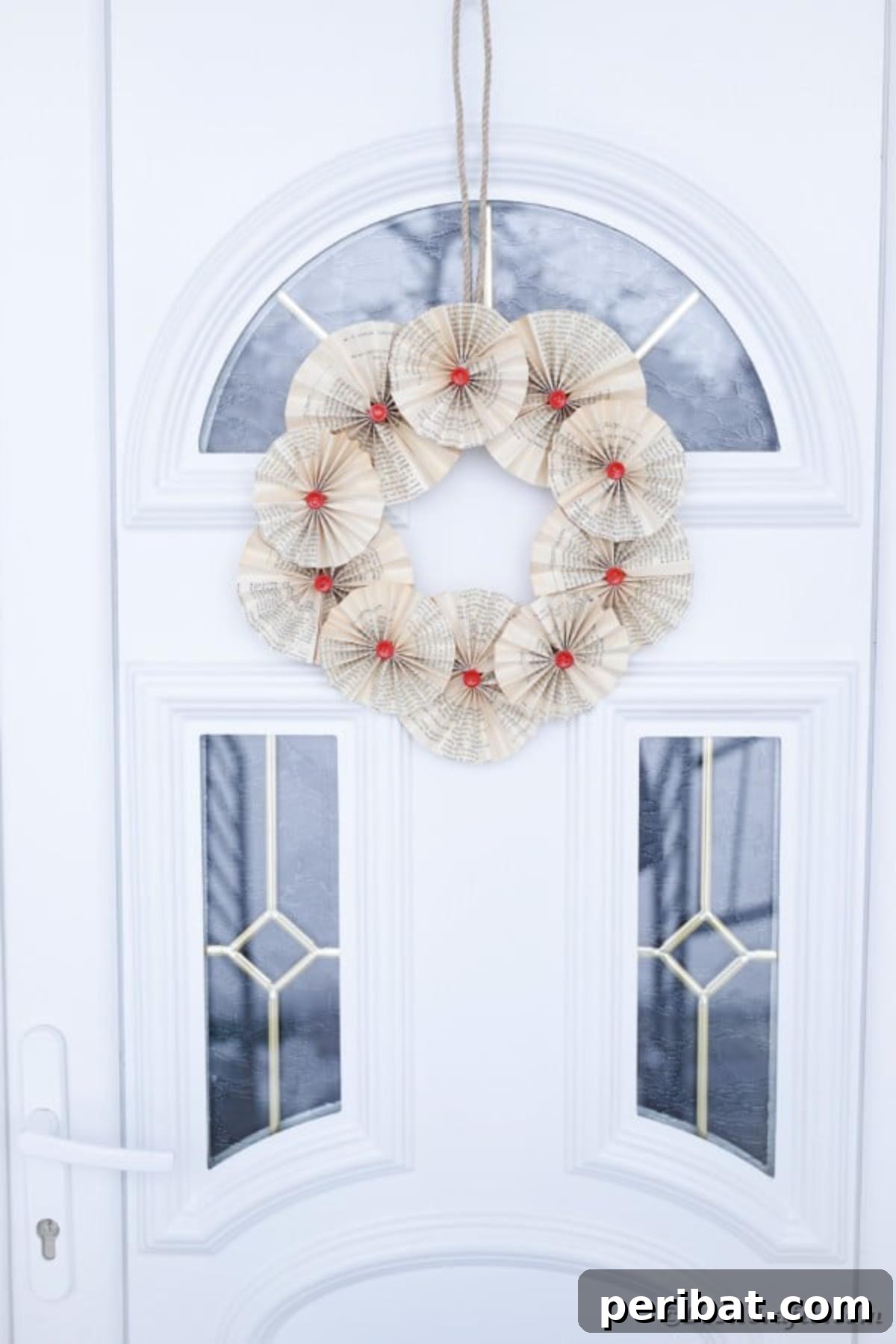 Enchanting Vintage Book Page Wreath Craft 3 A rustic old book page wreath hanging on a dark front door, accentuating its vintage appeal.