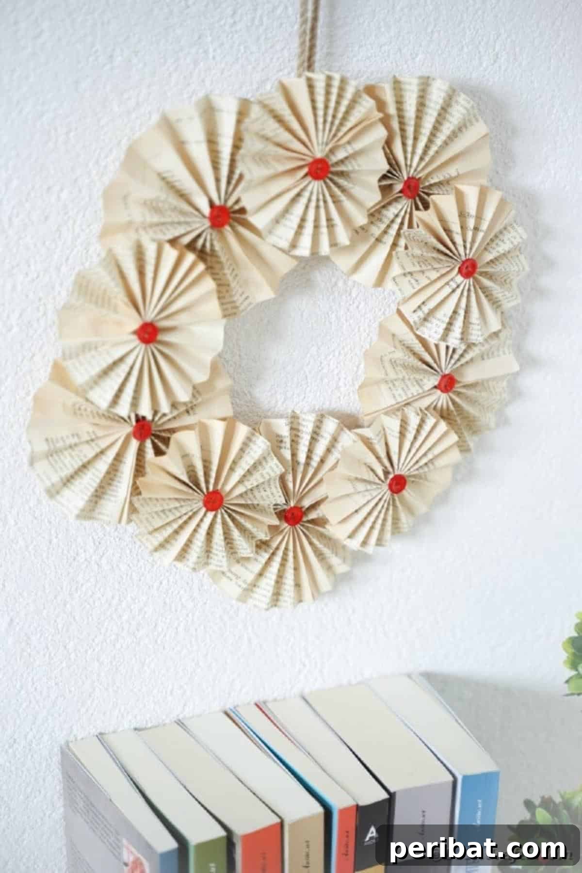 Enchanting Vintage Book Page Wreath Craft 5 A book page wreath adorning a wall above a stack of old books, creating a cozy and intellectual atmosphere.