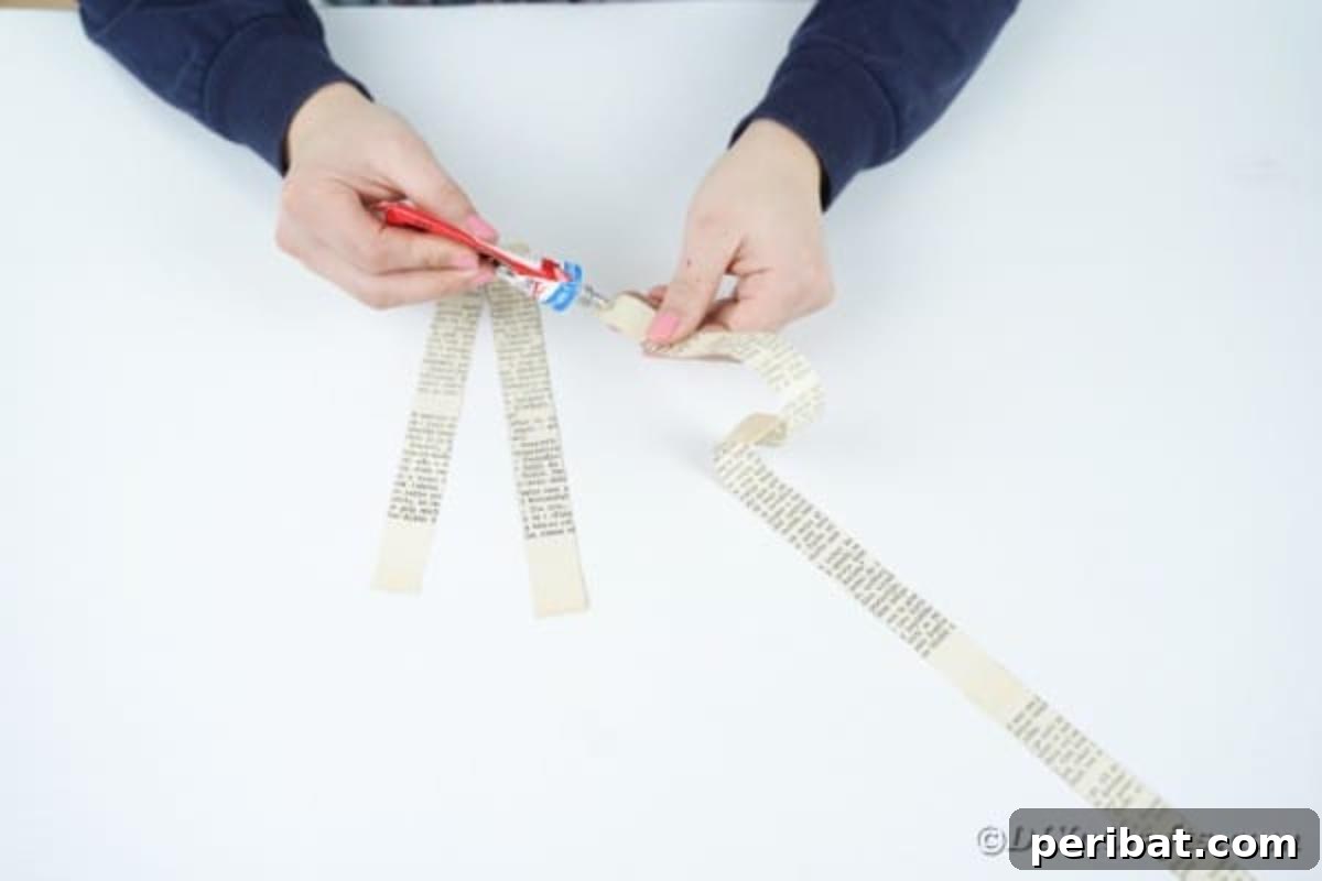 Craft glue being applied to the end of a paper strip, joining it with another to form a long 'paper ribbon'.