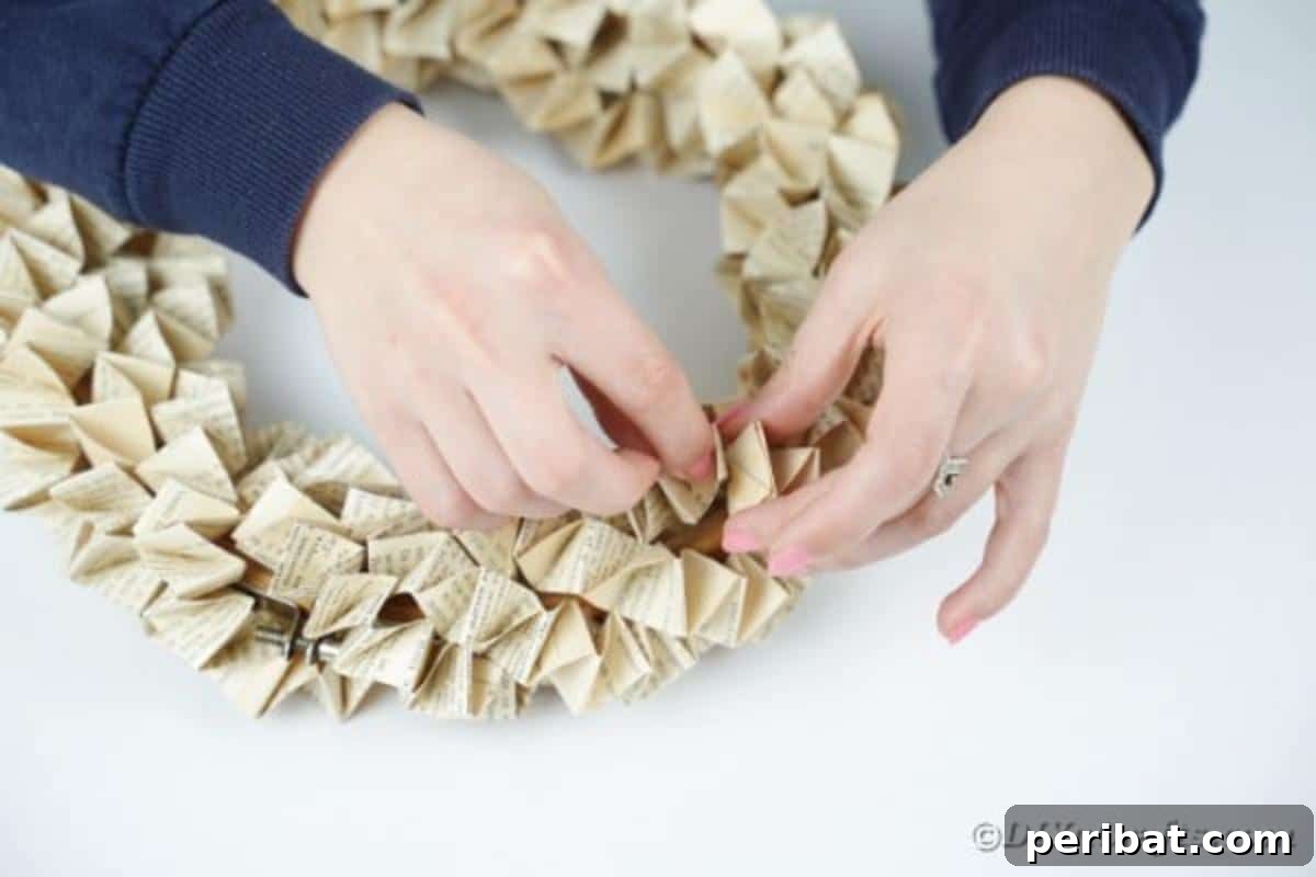 The book page wreath nearing completion, showcasing the layered and spiraled paper folds filling the embroidery hoop.