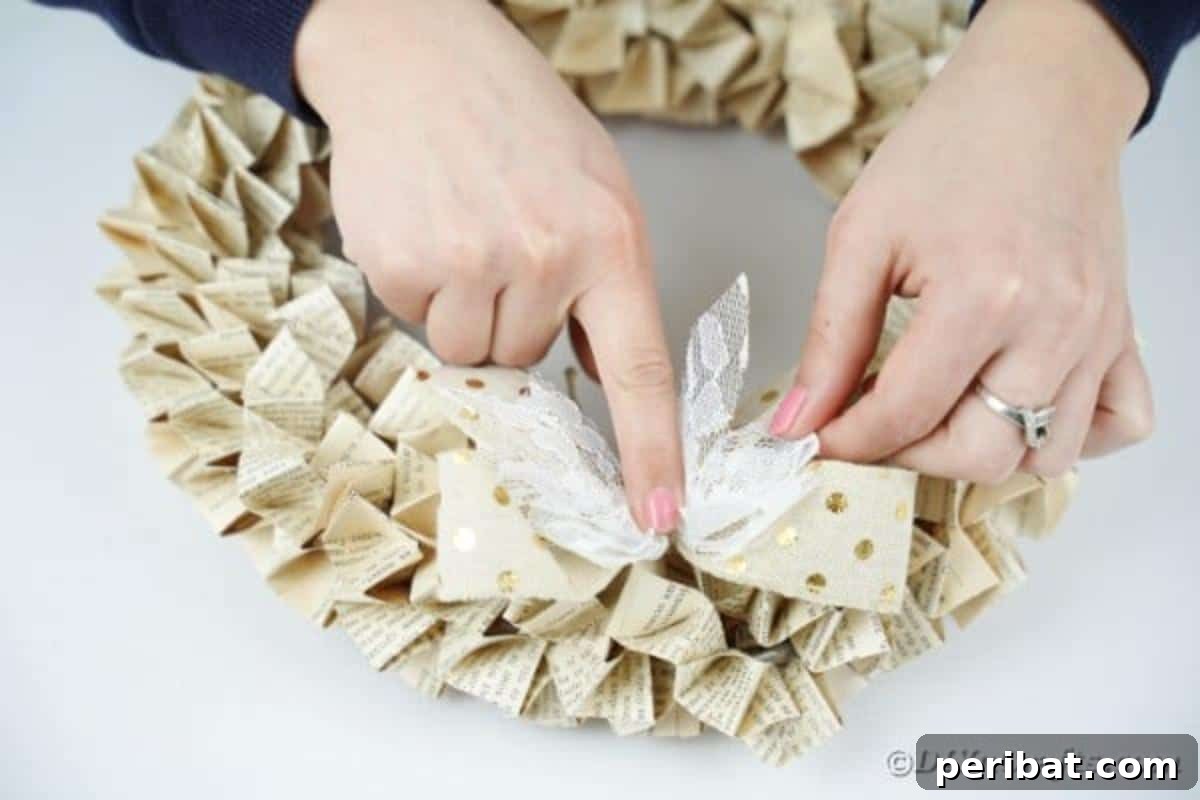 Close-up shot of decorative bows being glued onto the book page wreath, adding a finishing touch.