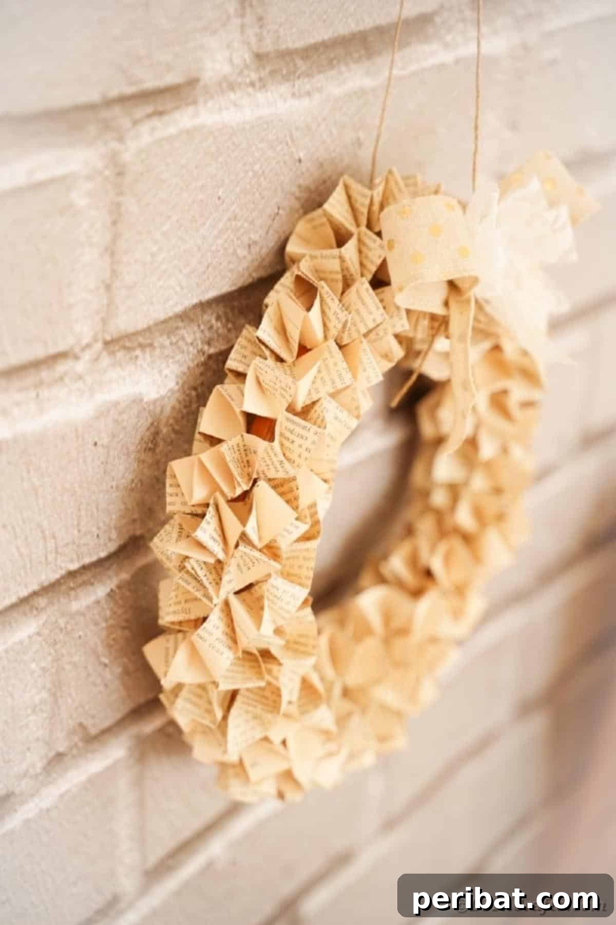 The completed Origami Book Page Wreath displayed beautifully on a brick wall, showcasing its rustic elegance.