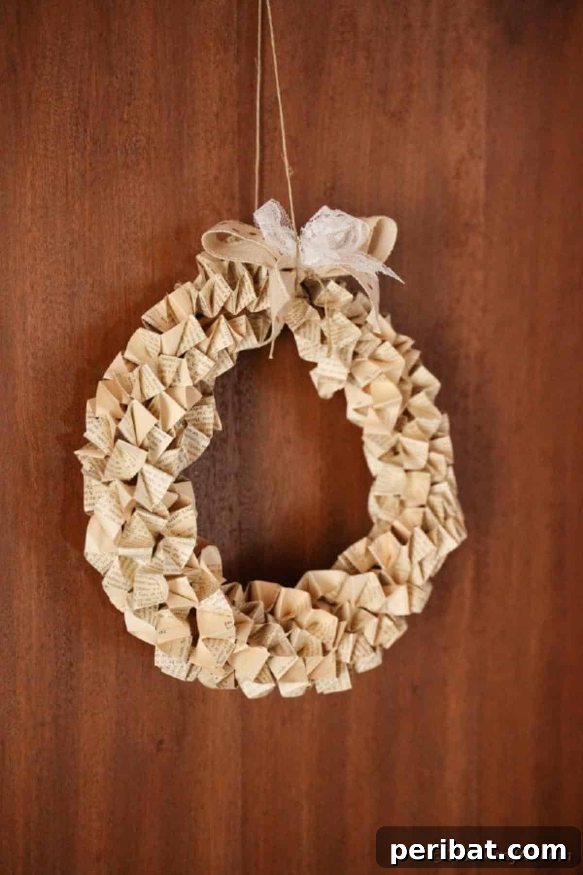 Close-up of a beautifully crafted book page wreath hanging on a rustic wooden wall, highlighting texture and detail.