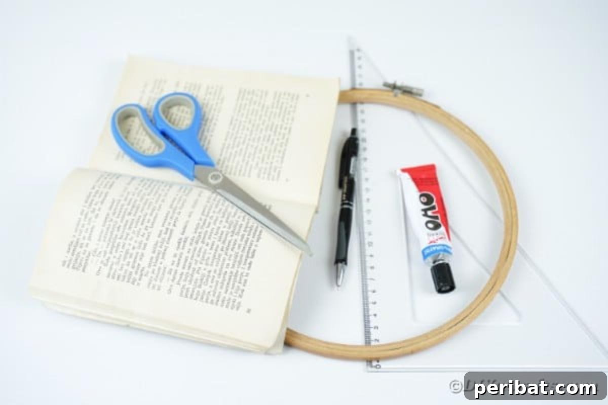 Various craft supplies laid out for making an Old Book Page Wreath, including books, an embroidery hoop, ribbon, glue, and scissors.