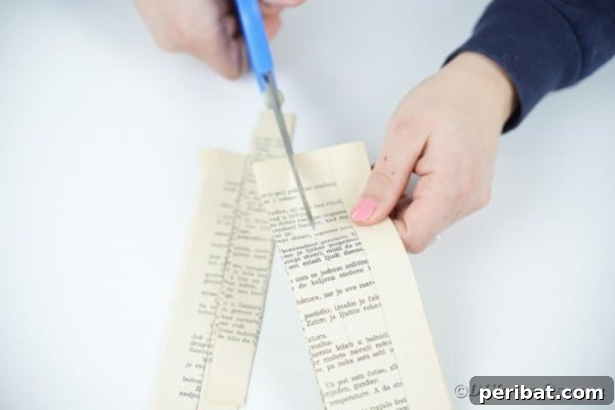 Hands using scissors to cut marked book pages into uniform paper strips.