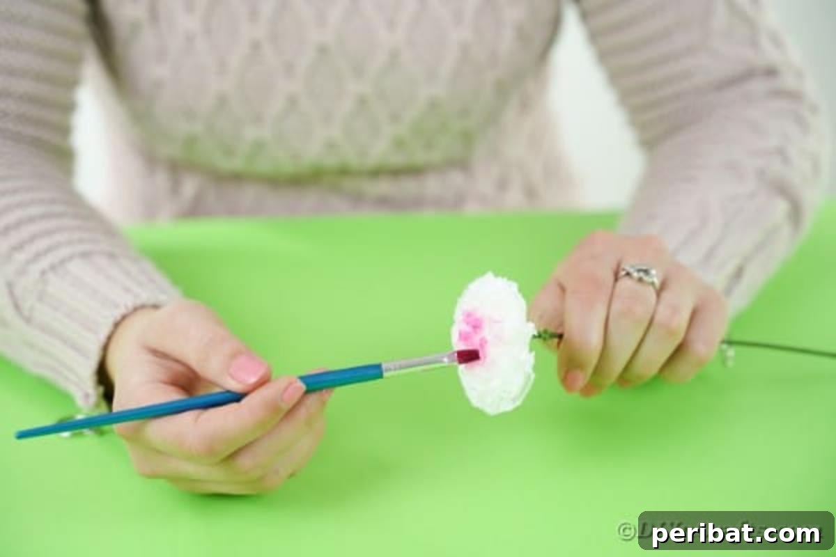 Craft Vibrant Tissue Blooms Video Tutorial 12 A paintbrush dabbing paint onto the petals of a tissue paper flower to add color accents