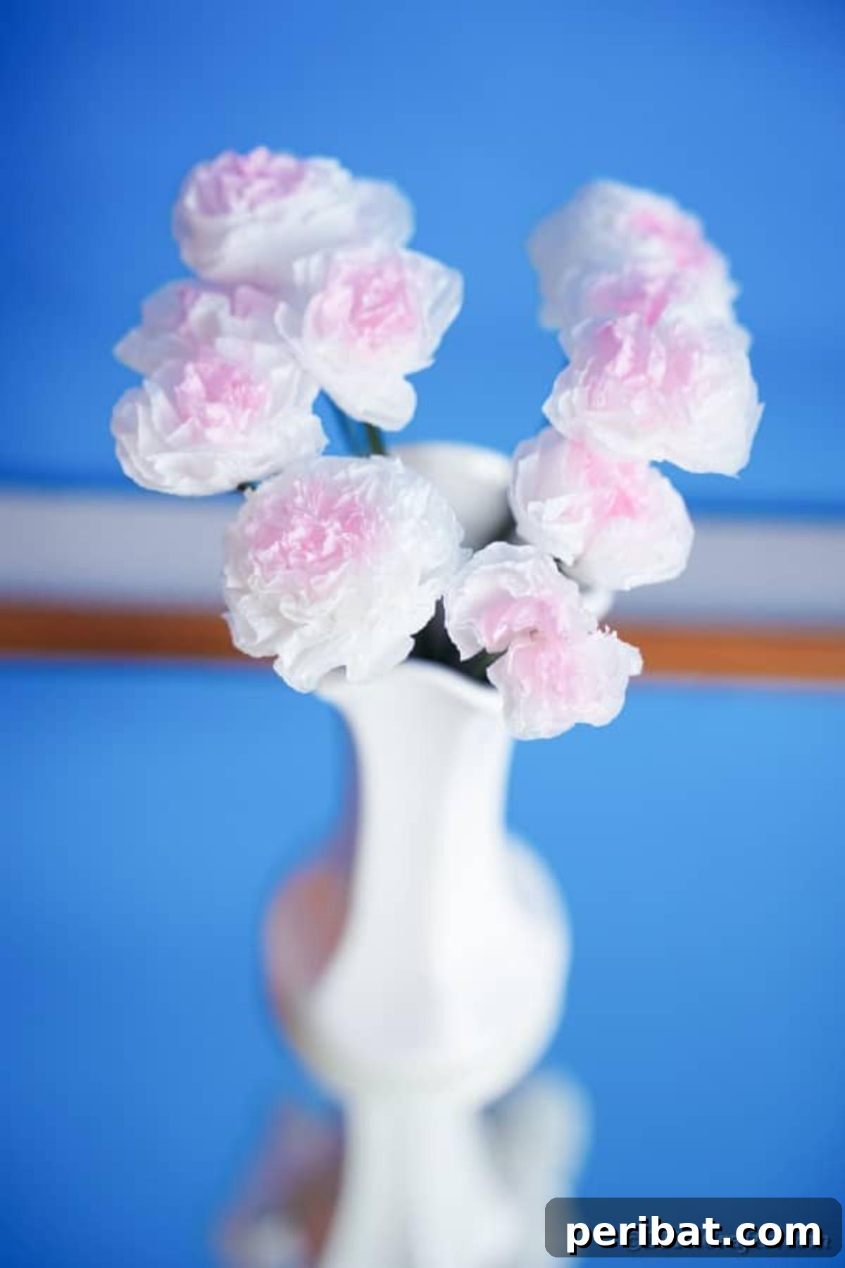 Craft Vibrant Tissue Blooms Video Tutorial 5 A bouquet of tissue paper flowers in a white vase against a soft blue background