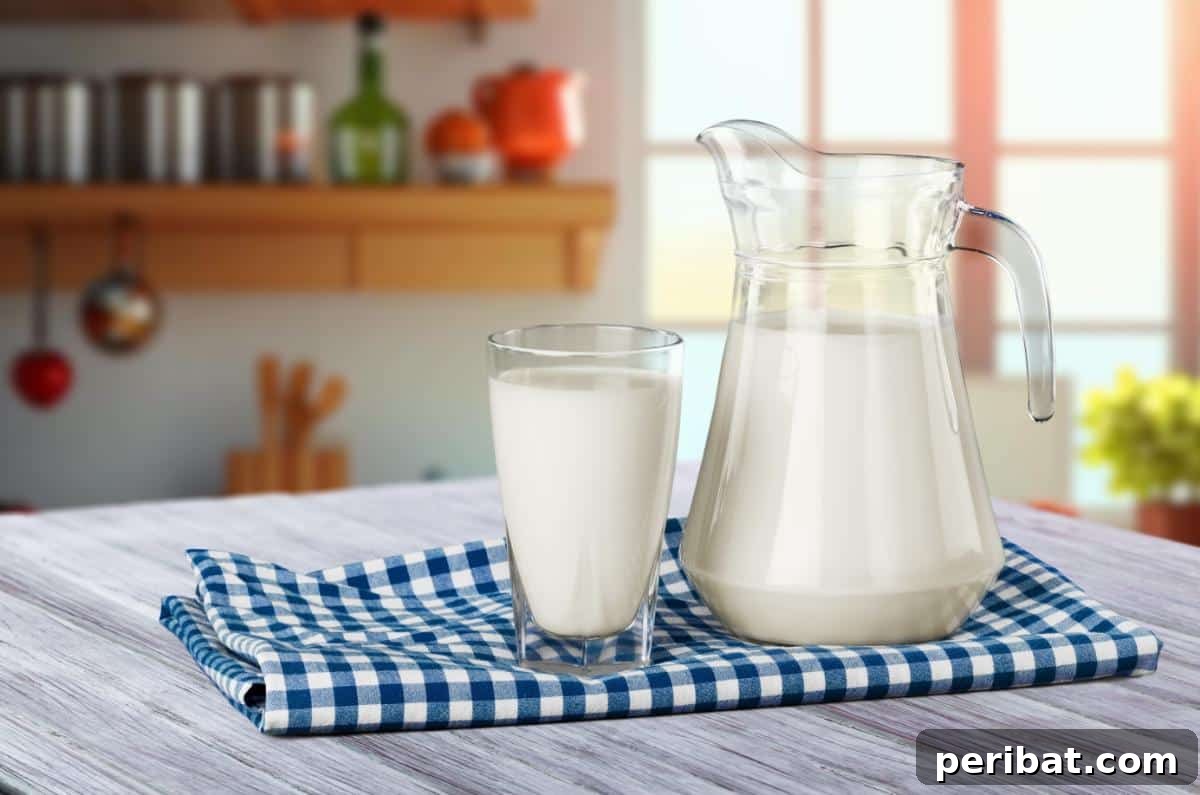 A pitcher and a glass full of fresh milk, highlighting its suitability for freezer storage to prevent spoilage.