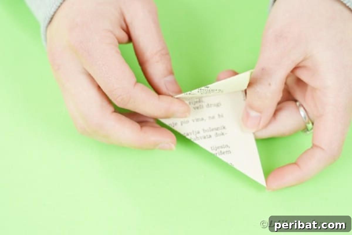 Close-up of hands holding a small, tightly folded paper triangle